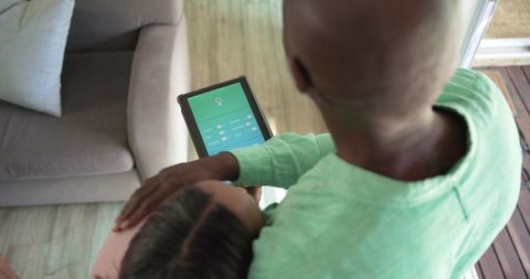 African american couple controlling smart home lighting with tablet in cozy living room