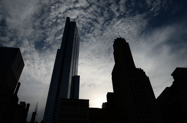 Silhouette of tall buildings under dramatic morning clouds. Perfect for depicting urban environments, real estate promotions, commercial districts, city ethos, and architectural development themes.