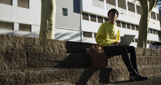 Young man in yellow sweater working on laptop outdoors - Download Free Stock Images Pikwizard.com