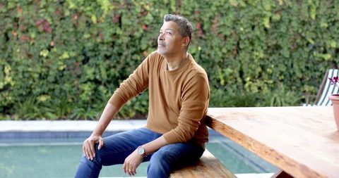 Senior man relaxing beside garden pool gazing thoughtfully