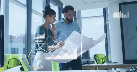 Colleagues Analyzing Blueprint in Modern Office with Digital Graphs