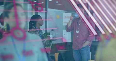Multicultural team brainstorming behind glass with pink marker notes and coffee break
