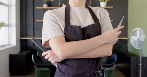 Hairdresser Holding Scissors and Comb in Modern Salon