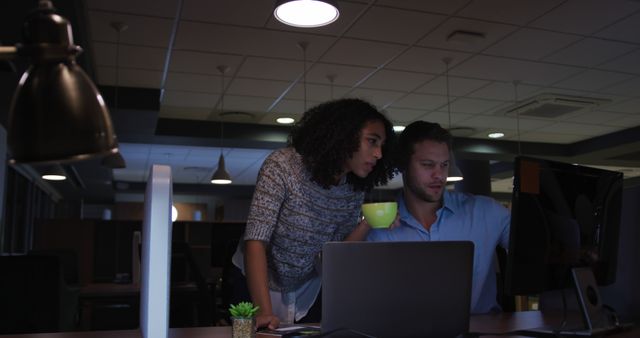 Two Colleagues Working Late at Office Using Desktop Computer and Laptop - Download Free Stock Images Pikwizard.com