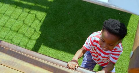 Child climbing wall on playground in sunny weather