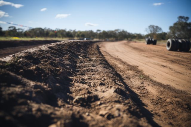 Dirt track in countryside with row of tyres, created using generative ai technology. Dirt track, racing and driving concept digitally generated image.