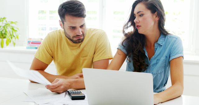 Worried couple calculating their bills with laptop in the kitchen at home