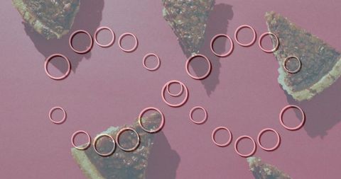 Metallic pink rings forming interlocking loops over pecan pie slices on dusty pink flatlay