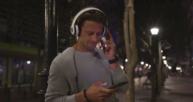 Man Enjoying Music on Smartphone with Headphones at Night - Download Free Stock Images Pikwizard.com