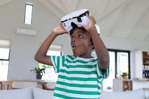 Excited african american boy trying white vr headset in modern living room