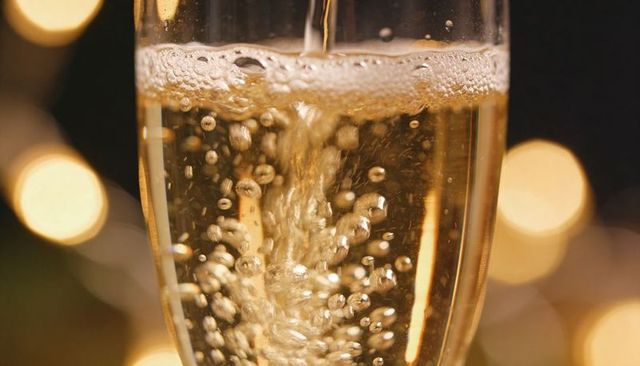 Pouring champagne flute with golden bubbles and warm bokeh glow
