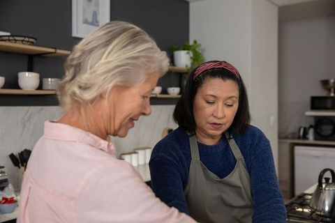 Older and middle-aged women cooking together in cozy modern kitchen