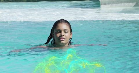 Floating teen girl in turquoise pool with neon mesh overlay, summer leisure portrait