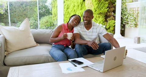 Smiling Couple Using Laptop While Relaxing At Home