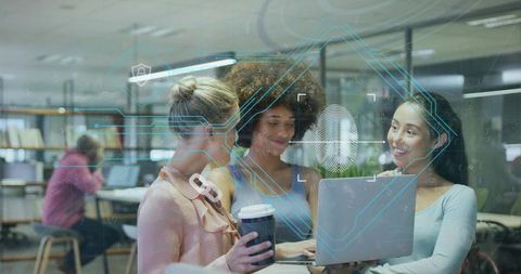 Collaborating women around laptop viewing biometric fingerprint overlay at coworking office