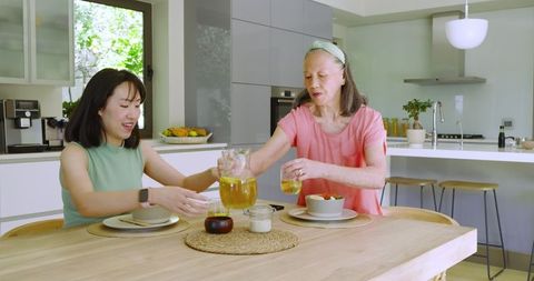 Mother and Daughter Enjoying Juice Together in Modern Kitchen