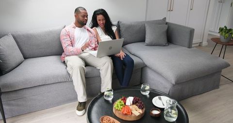 Couple celebrating engagement at home with technology