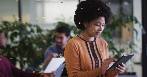 Using tablet in coworking space for teamwork with plants, laptop and gold star overlay