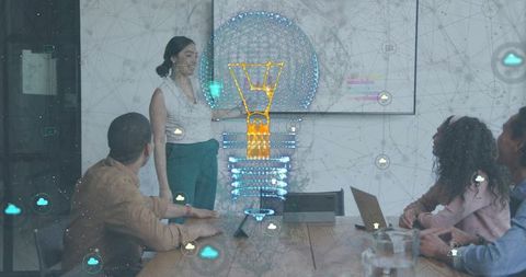 Team presenting holographic lightbulb around conference table driving digital innovation