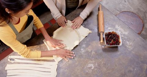 Mother and daughter baking together flattening dough