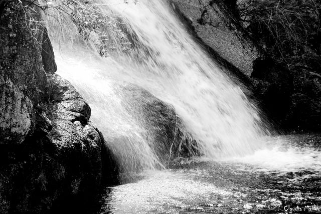 This image features a cascading waterfall flowing over rocks captured in black and white, highlighting the textures and the movement of the water. Ideal for use in nature-focused projects, environmental awareness campaigns, or as artistic decor. Use it to evoke a sense of calmness and natural beauty.