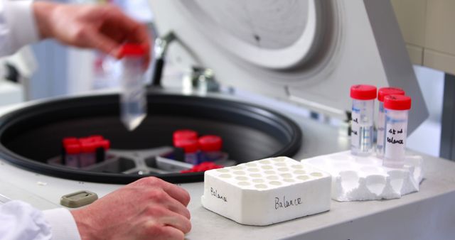 Scientist handling samples in a high-tech laboratory setting. The image features a centrifuge with test tubes, focusing on the precise and careful handling of biological or chemical samples. This image is perfect for illustrating scientific research, healthcare innovations, and advancements in biotechnology. It can be used in medical and research publications, educational materials, and advertisements for laboratory equipment.