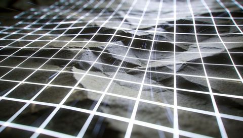 Projecting luminous grid bending over rocky terrain showing warped lattice crater depth