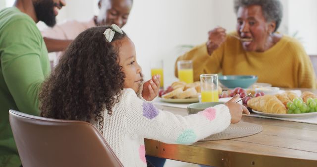 Image of happy african american parents, daughter and grandparents eating at dinner table. Family, domestic life and togetherness concept digitally generated image.