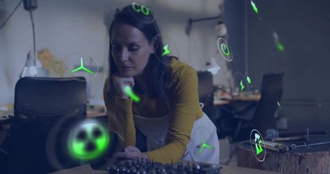 Female Technician Leaning Over Bearings in Modern Workshop with Green Energy Icons