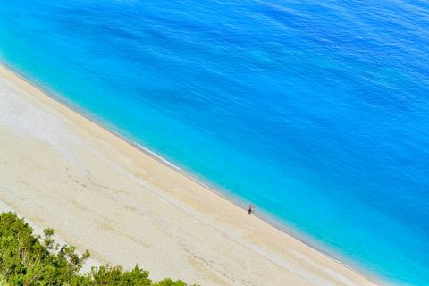 Solitary Figure Walking Pristine Turquoise Shoreline from Aerial Perspective Minimal Beachscape