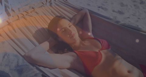 Beach relaxation: woman lounging in hammock under sunlight