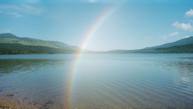 Rainbow Arch Over Calm Lake with Mountain Background