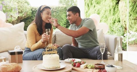 Joyful Couple Celebrating Anniversary with Cake and Champagne Outdoors