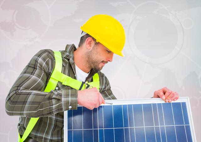 Electrician wearing yellow helmet and safety gear fixes solar panel. Background shows map. Ideal for advertisements, informational content on renewable energy, clean energy initiatives, or global sustainability efforts.