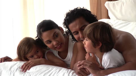 Happy Family Relaxing and Bonding on Bed at Home