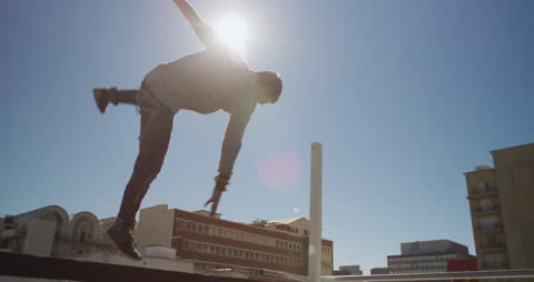 Man Practicing Parkour on Rooftop in Urban Setting on Sunny Day