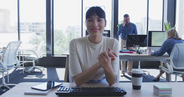 Smiling Businesswoman at Workstation with Colleagues in Modern Office - Download Free Stock Images Pikwizard.com