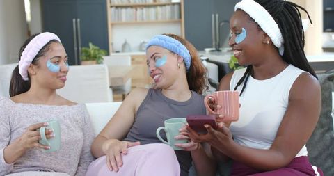 African american friends enjoying cozy at-home spa night with eye patches and coffee