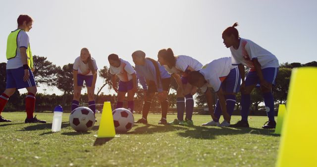 Team of diverse female football players with coach resting on sunny sports field - Download Free Stock Photos Pikwizard.com