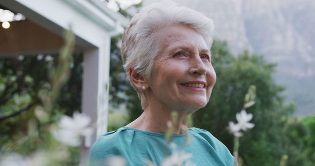 Happy, smiling senior caucasian woman in garden looking into the distance. Relaxation, senior lifestyle and retirement.