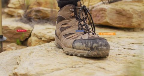 Mud-covered hiking boot on sandstone rock