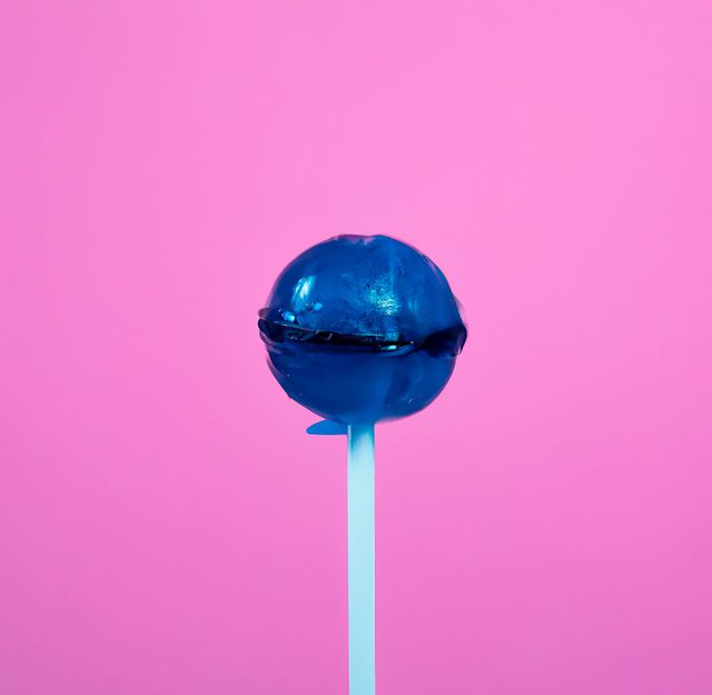 Close up of round blue lollipop on pink background. Candy, sweets, food and drink concept.