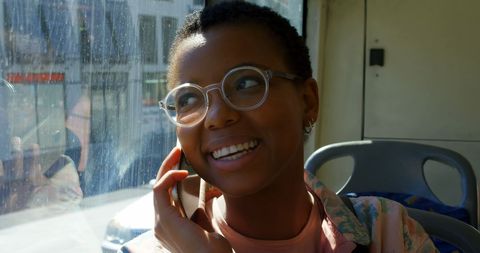 Joyful commuter chatting on mobile phone in sunlit bus
