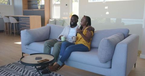 Couple Relaxing on Sofa Enjoying Coffee and Conversation at Home