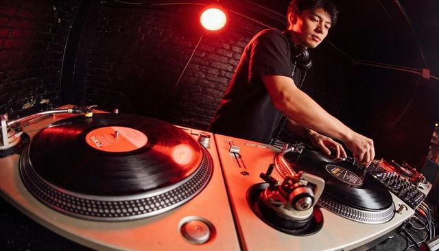Mixing dj cueing vinyl turntables under red club lighting for nightlife vibes