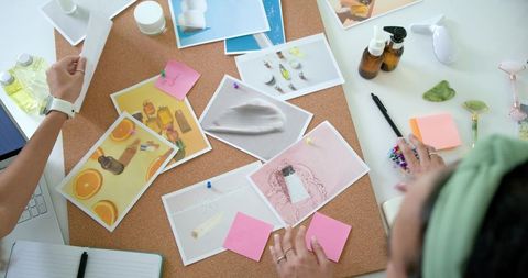 Arranging beauty product moodboard on corkboard for skincare branding and packaging design