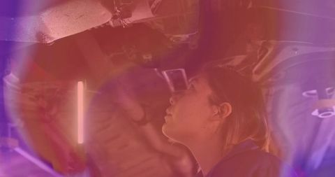 Female auto technician inspecting under car in garage