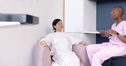 Calm clinical consultation between patient in gown and clinician using digital tablet