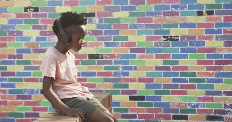 Child Listening to Music with Headphones near Colorful Mural