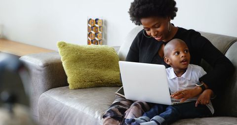 African American Mother and Son Using Laptop on Couch